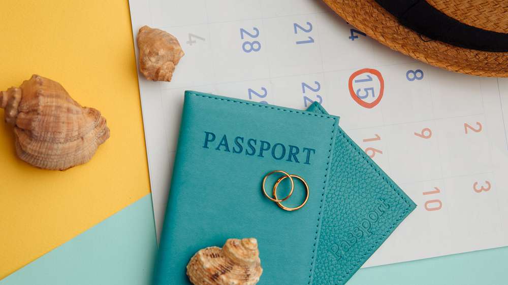 calendar with passports hat and rings on colorful surface honeymoon wedding concept date of travelling